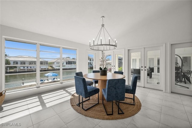 dining space with plenty of natural light, a water view, french doors, and an inviting chandelier