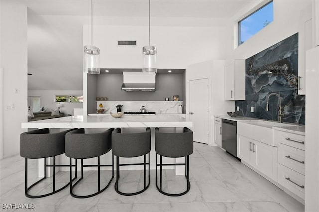 kitchen featuring a kitchen bar, tasteful backsplash, hanging light fixtures, stainless steel dishwasher, and white cabinets