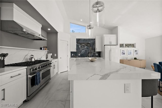 kitchen featuring white cabinets, wall chimney range hood, white fridge, double oven range, and hanging light fixtures