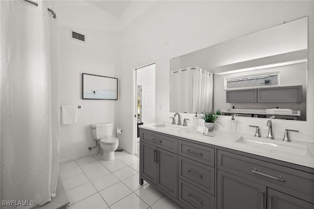 bathroom featuring toilet, vanity, a towering ceiling, and tile patterned floors