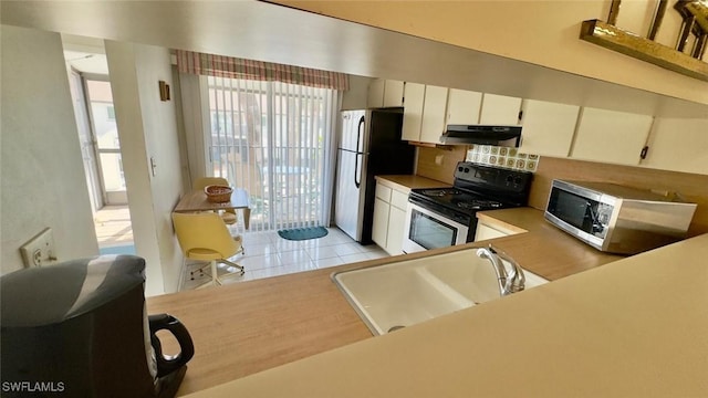 kitchen featuring white cabinets, appliances with stainless steel finishes, tasteful backsplash, sink, and light tile patterned flooring