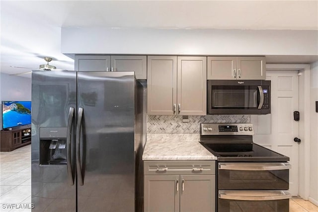 kitchen with ceiling fan, gray cabinets, light tile patterned flooring, decorative backsplash, and stainless steel appliances