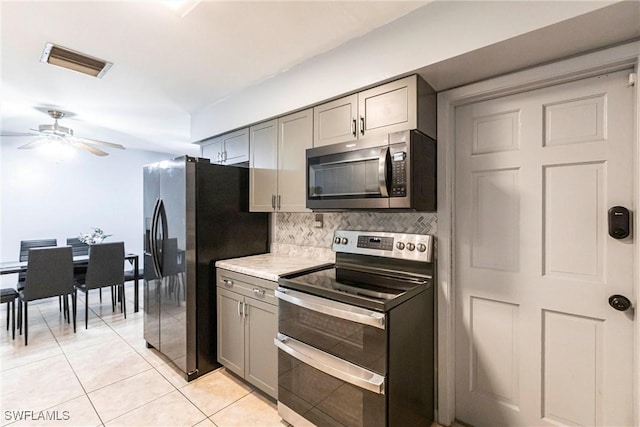 kitchen with tasteful backsplash, gray cabinetry, light tile patterned floors, and stainless steel appliances