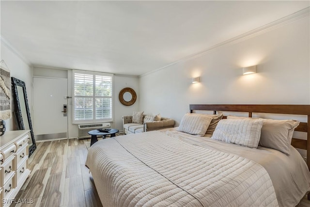 bedroom with light wood-type flooring, a wall unit AC, and ornamental molding