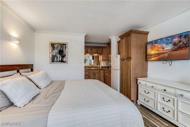 bedroom with a sink, wood finished floors, ornamental molding, and freestanding refrigerator