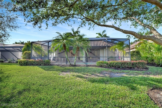 back of property with a lanai and a lawn