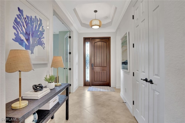 tiled entrance foyer with crown molding and a tray ceiling