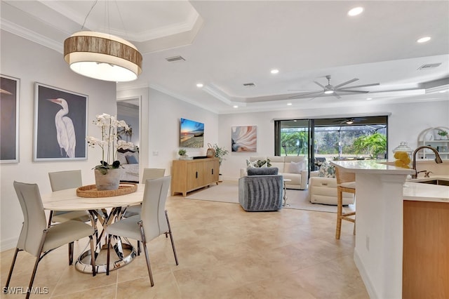 dining room with crown molding, ceiling fan, a tray ceiling, and sink