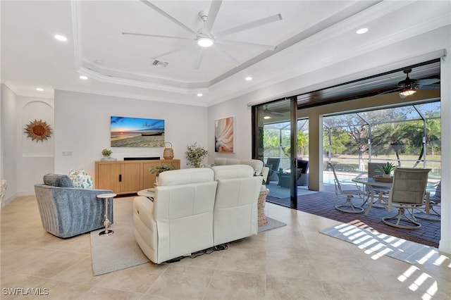 living room featuring a tray ceiling, ornamental molding, ceiling fan, and light tile patterned flooring