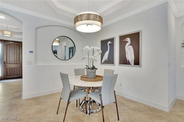 tiled dining room featuring crown molding and a tray ceiling