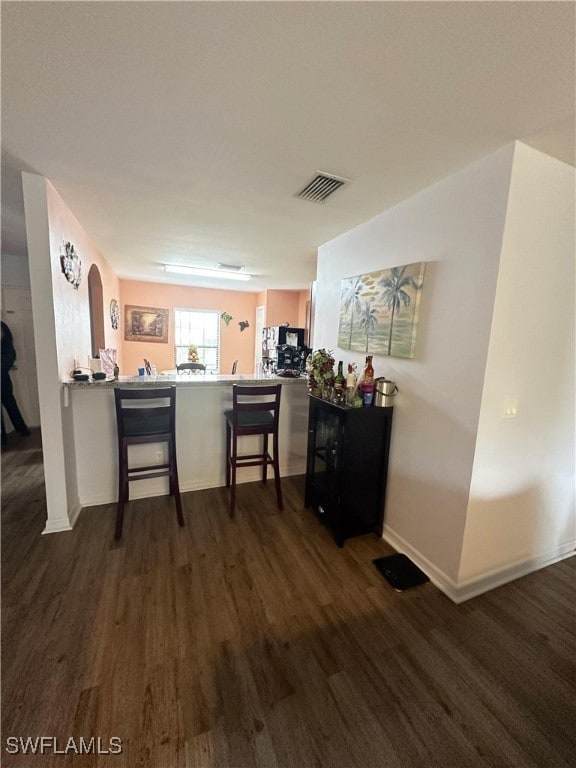 kitchen with a breakfast bar, kitchen peninsula, and dark hardwood / wood-style floors