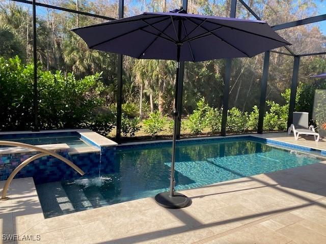 view of swimming pool with an in ground hot tub, a lanai, and a patio