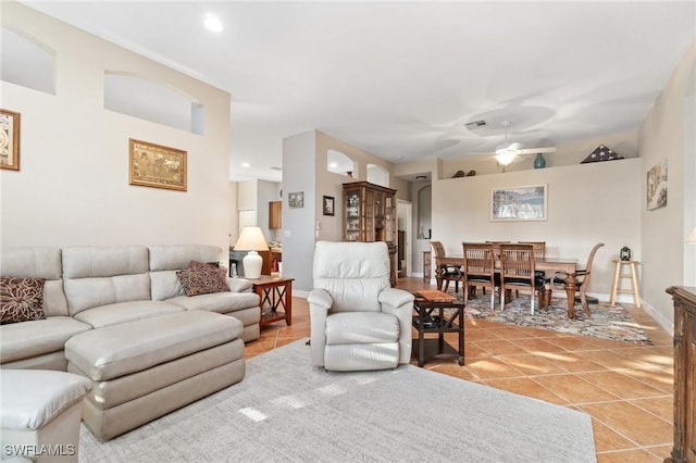 living area featuring ceiling fan, baseboards, and light tile patterned flooring