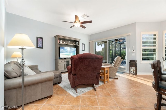 living area featuring light tile patterned floors, baseboards, visible vents, and a ceiling fan