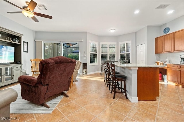 kitchen with a center island, light tile patterned floors, backsplash, and light stone counters