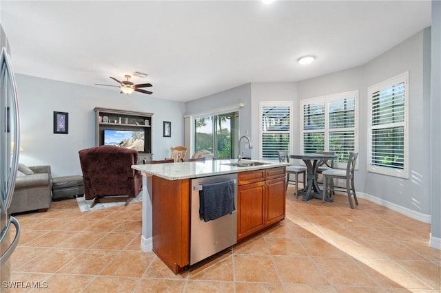 kitchen with sink, light tile patterned floors, a kitchen island with sink, light stone countertops, and stainless steel dishwasher