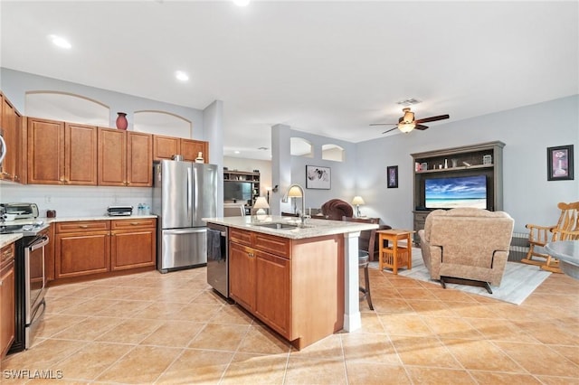 kitchen with stainless steel appliances, a sink, open floor plan, an island with sink, and a kitchen bar