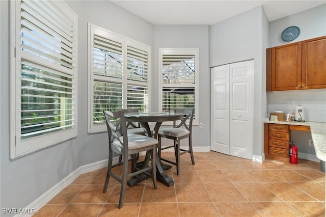 dining room with light tile patterned flooring, built in desk, and baseboards