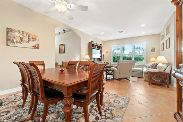 dining space with a ceiling fan, arched walkways, baseboards, and light tile patterned floors