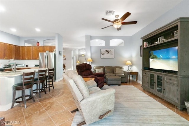 living room with light tile patterned floors, ceiling fan, arched walkways, and visible vents