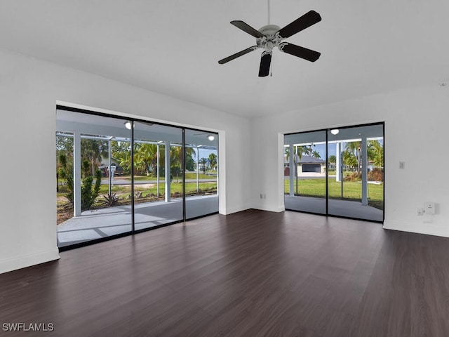 spare room featuring ceiling fan, a wealth of natural light, and dark wood-type flooring