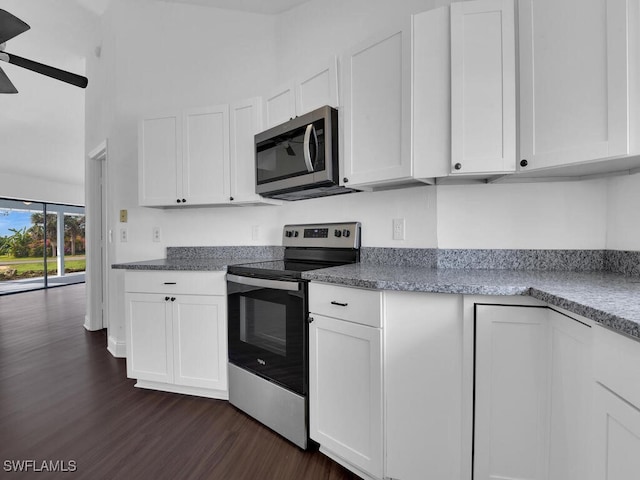 kitchen with light stone counters, dark hardwood / wood-style flooring, white cabinetry, and stainless steel appliances