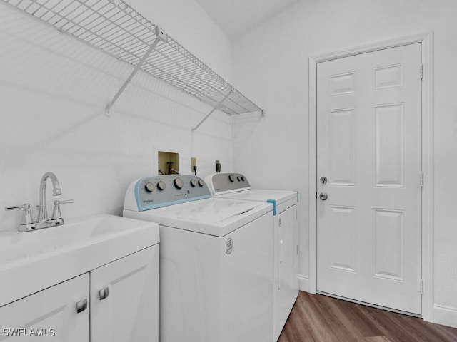 laundry room featuring sink, hardwood / wood-style floors, cabinets, and washer and dryer