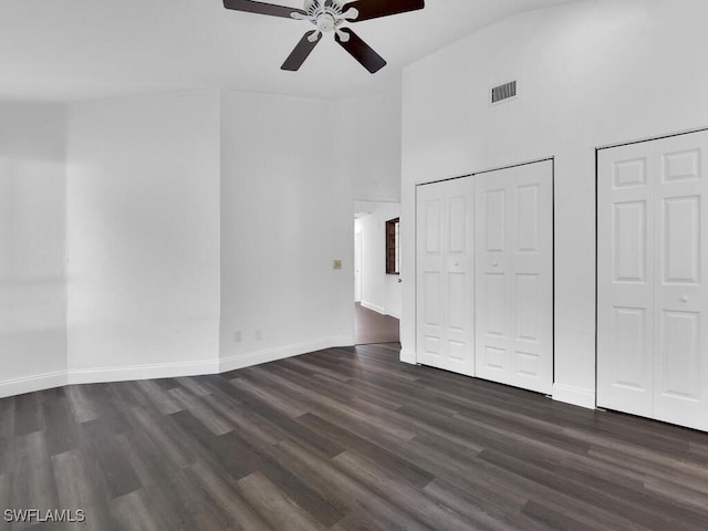 unfurnished living room with ceiling fan, dark hardwood / wood-style floors, and high vaulted ceiling