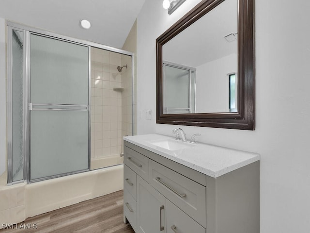 bathroom with hardwood / wood-style flooring, enclosed tub / shower combo, and vanity