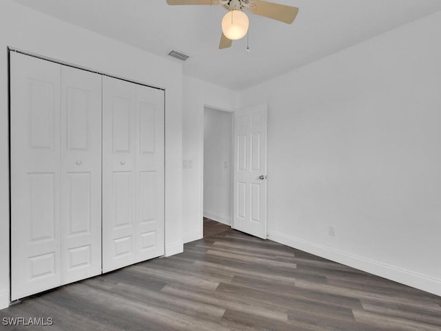 unfurnished bedroom with dark wood-type flooring, a closet, and ceiling fan