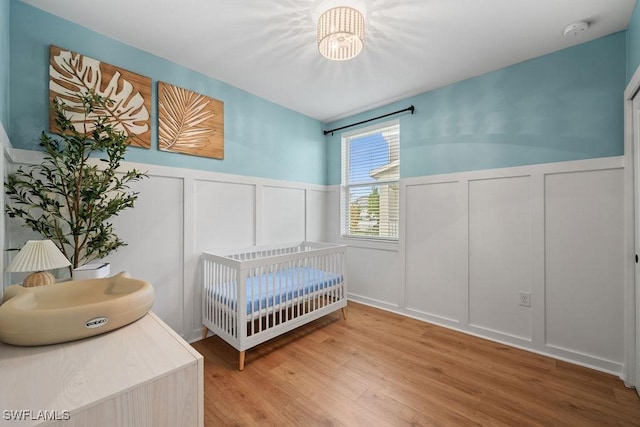 bedroom featuring wood-type flooring and a nursery area