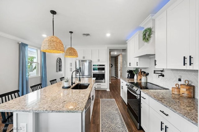 kitchen with appliances with stainless steel finishes, a center island with sink, and a breakfast bar area