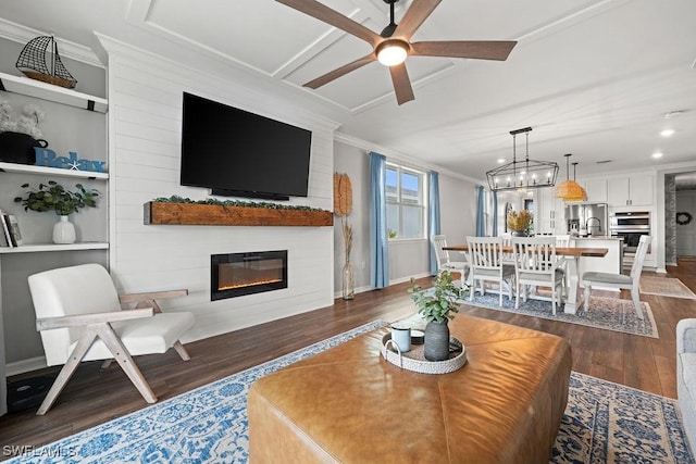 living room featuring dark wood-type flooring, sink, ceiling fan with notable chandelier, and ornamental molding