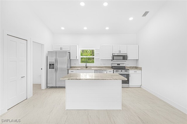 27159 Alhambra Dr, Punta Gorda, FL 33955 - kitchen with stainless steel appliances, a sink, white cabinets, a kitchen island, and recessed lighting