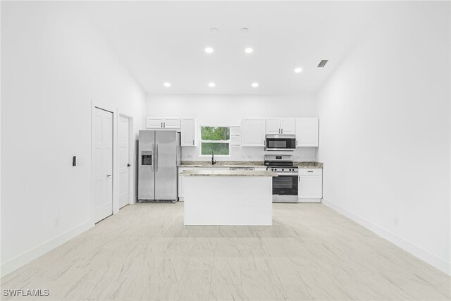27159 Alhambra Dr, Punta Gorda, FL 33955 - kitchen with appliances with stainless steel finishes, white cabinets, a center island, recessed lighting, and baseboards