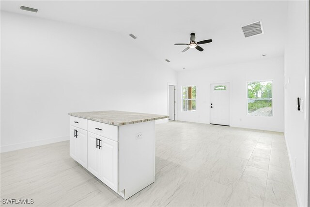 27159 Alhambra Dr, Punta Gorda, FL 33955 - kitchen with ceiling fan, lofted ceiling, white cabinetry, baseboards, and a center island