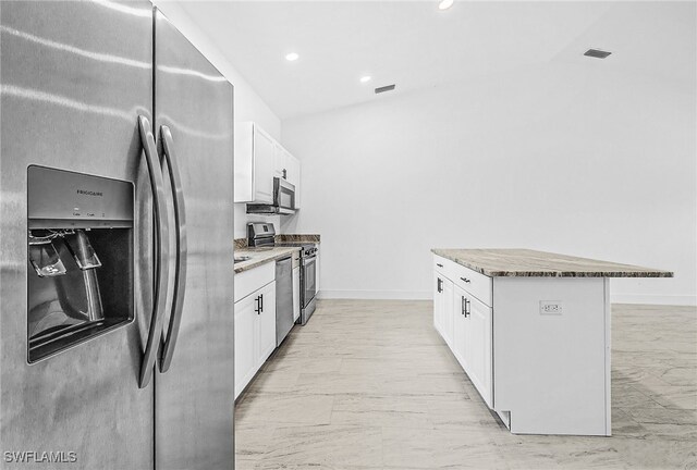 27159 Alhambra Dr, Punta Gorda, FL 33955 - kitchen featuring appliances with stainless steel finishes, light marble finish floors, a center island, white cabinets, and baseboards