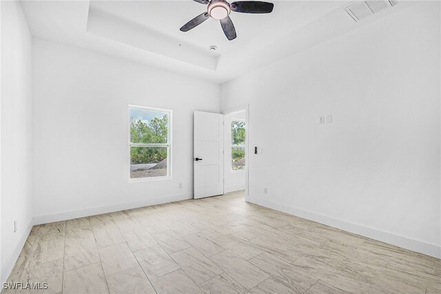 27159 Alhambra Dr, Punta Gorda, FL 33955 - empty room featuring a raised ceiling, baseboards, a ceiling fan, and marble look tile flooring