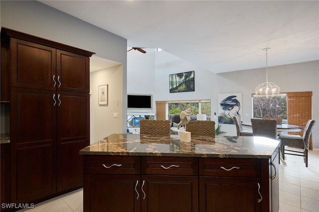 kitchen featuring hanging light fixtures, dark stone countertops, ceiling fan with notable chandelier, and a center island