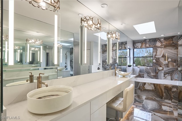 bathroom with a bath, a skylight, and vanity