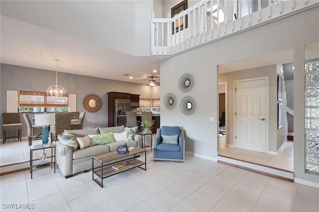 tiled living room with ceiling fan with notable chandelier and a towering ceiling