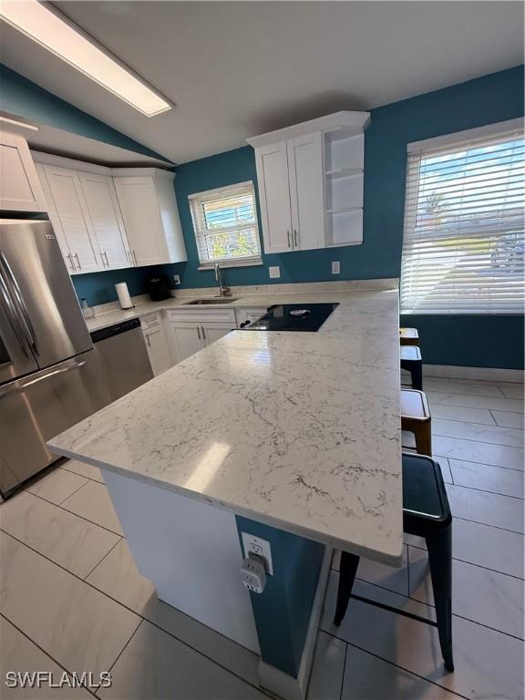 kitchen with white cabinetry, sink, a breakfast bar, and vaulted ceiling