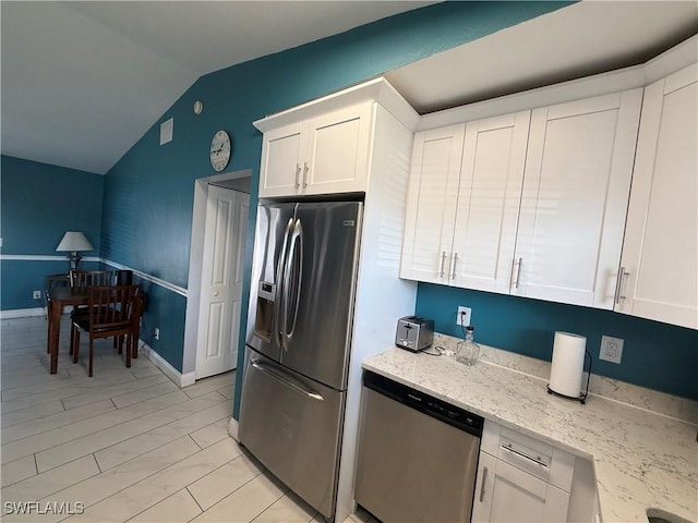 kitchen with white cabinetry, light stone countertops, vaulted ceiling, and stainless steel appliances