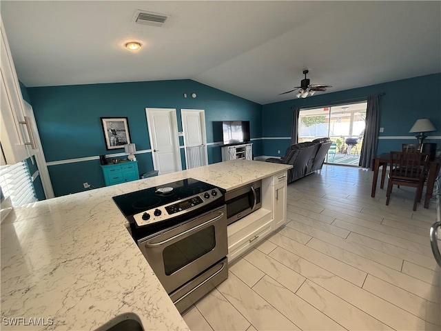 kitchen with lofted ceiling, ceiling fan, appliances with stainless steel finishes, white cabinetry, and light stone counters