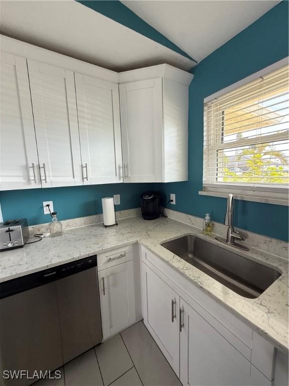 kitchen with lofted ceiling, sink, dishwasher, white cabinetry, and light stone countertops