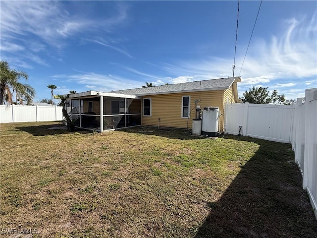 rear view of house featuring a lawn and a sunroom