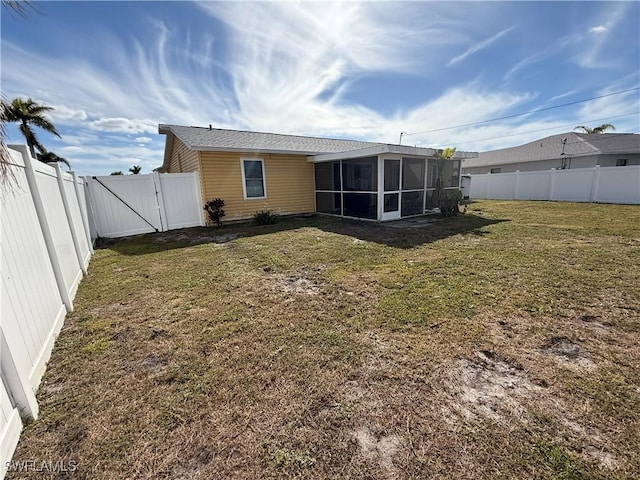 rear view of house with a sunroom and a yard