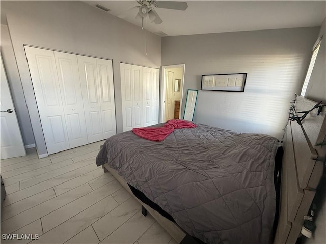 bedroom featuring multiple closets, lofted ceiling, and ceiling fan