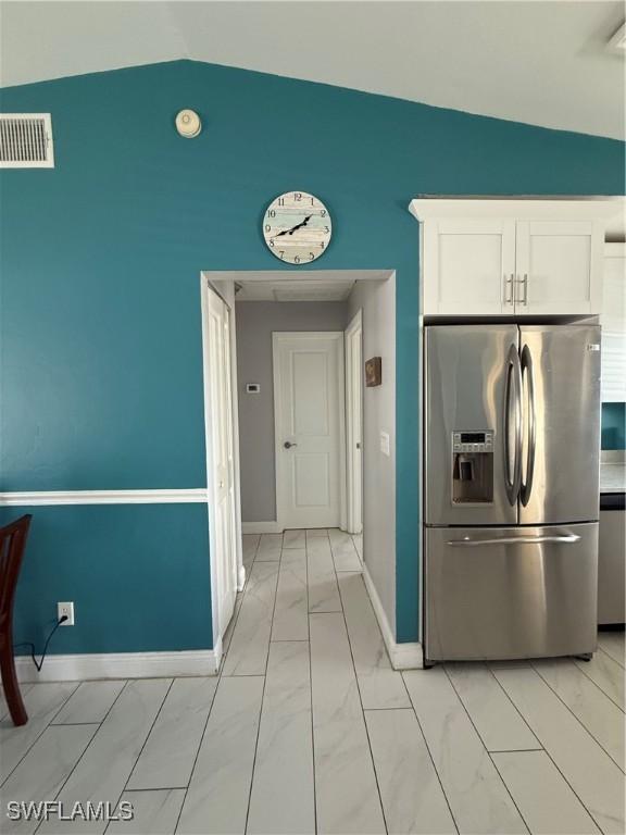 kitchen featuring vaulted ceiling, white cabinetry, and appliances with stainless steel finishes