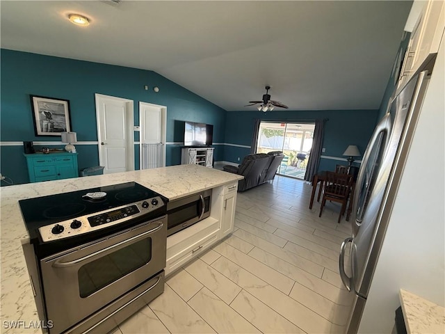 kitchen featuring vaulted ceiling, white cabinetry, ceiling fan, stainless steel appliances, and light stone countertops